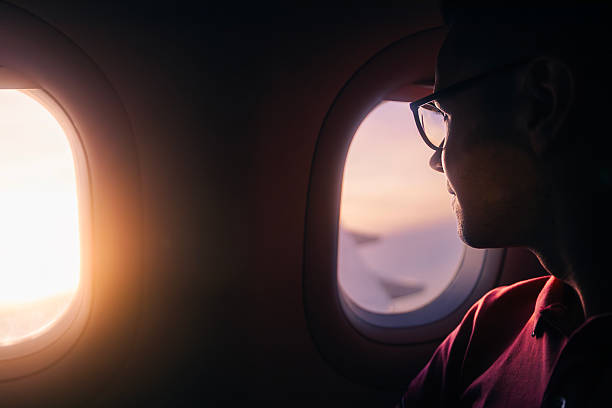 istock Passenger looking out airplane window at sunset during flight 2260267429