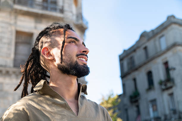 Man with dreadlocks and beard looking up outdoors, reflecting freedom and lifestyle