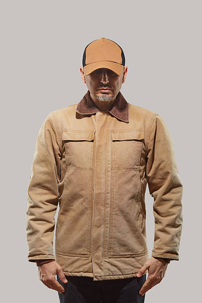 Man wering canvas work coat against white bakcground