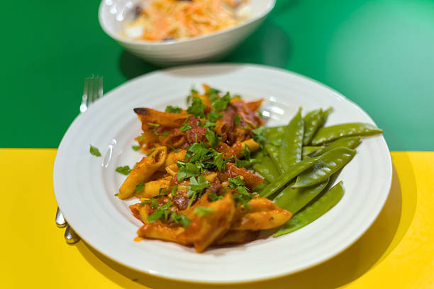Tomato and Cheddar Cheese Penne Pasta Bake with Green Snap Beans on Green and Yellow Background