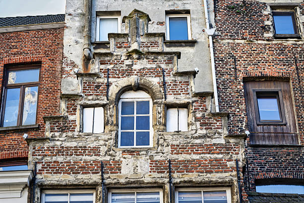 Unusual mix of a historic brick stepped gable, modern windows, and weathered plaster on an old building in Antwerp, Belgium. A study in urban decay