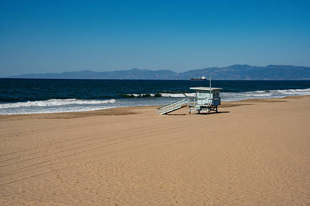 View through a sand fence towards a white lifeguard stand on the Californian coast