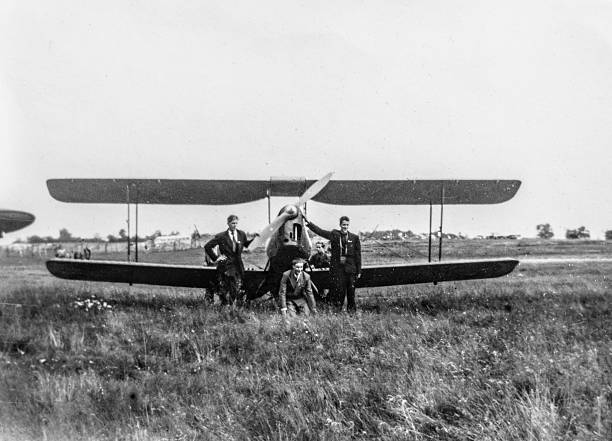 Sweden-May, 1940: Group of men posing with early propeller biplane aircraft on grassy airfield