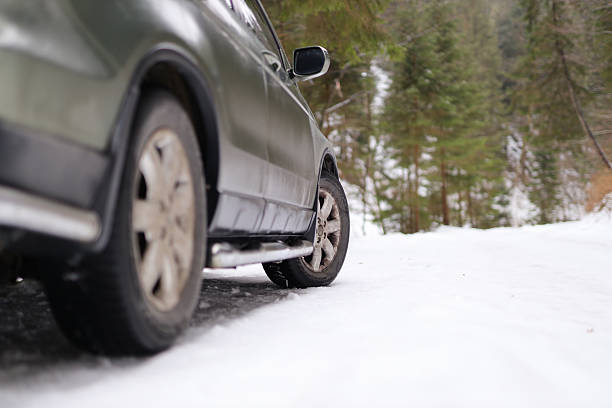 Car driving on snowy mountain road in winter forest scenery.