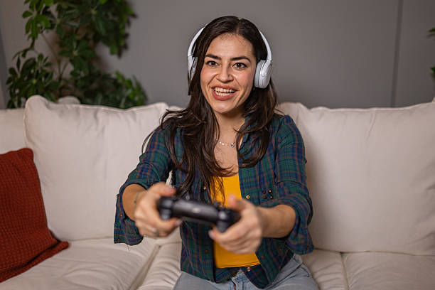 Young adult woman enjoying a video game while wearing headphones on sofa
