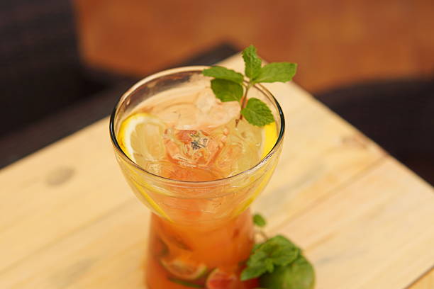 Refreshing iced drink garnished with lemon slices and fresh mint leaves, served on a light wooden table