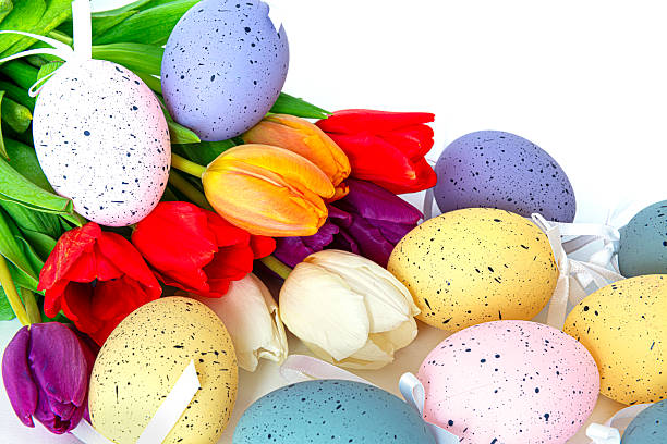 Easter colored eggs on green grass around tulips and wooden board Happy Easter