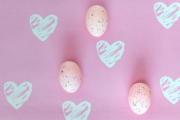 Three spotted Easter eggs on pink background with roughly drawn hearts in white.