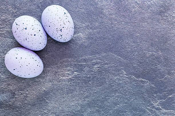 Three spotted Easter eggs positioned in top left hand corner of a purple slate table.