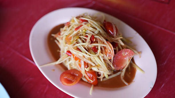 Spicy papaya salad features shredded green papaya, tomatoes, and chili peppers, creating vibrant and flavorful dish