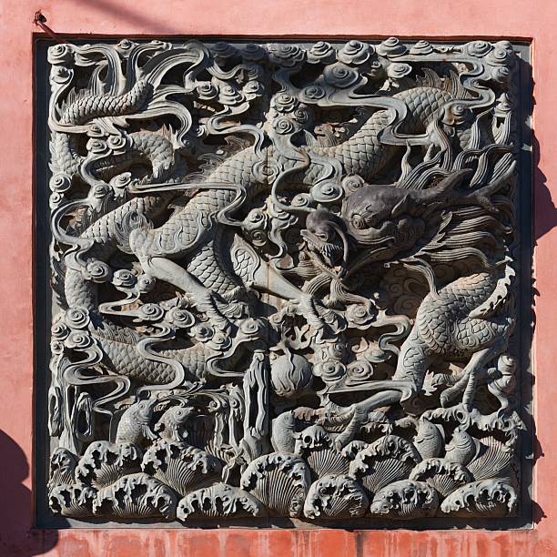 Intricate stone relief carving depicting dragons amidst clouds and waves