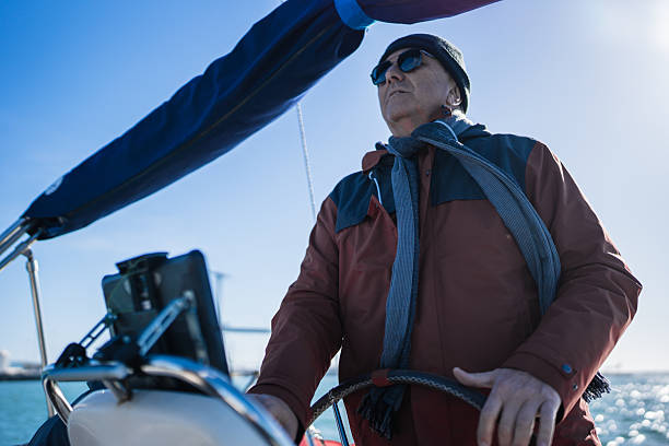 Senior man steering a sailboat on a sunny day, enjoying sailing adventure