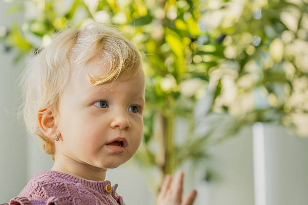Portrait of a cute blond boy of European appearance with a red flower