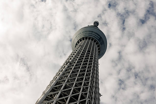 Looking straight up the latticework structure of the Tokyo Skytree. The white steel tower contrasts with a textured sky.