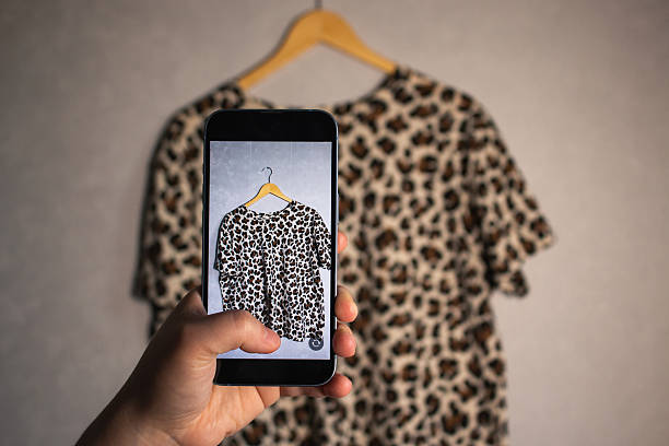 Close up of hands holding smartphone camera capturing old clothes items for online resale resources. Image for second hand concept.