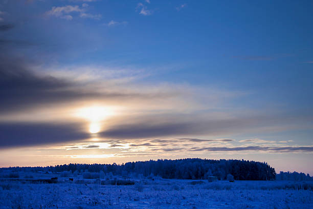 Golden Sunlight Breaking Through Clouds Over Winter Landscape