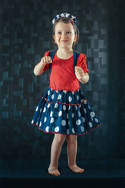 Smiling little girl looking up while wearing a red shirt and polka dot skirt
