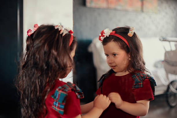 Child looking at her reflection in the mirror, exploring self-awareness and childhood curiosity