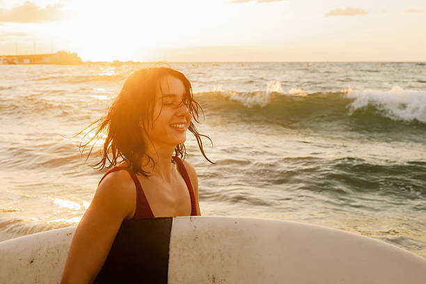istock Young woman enjoying sunrise surfing with surfboard 2260384802