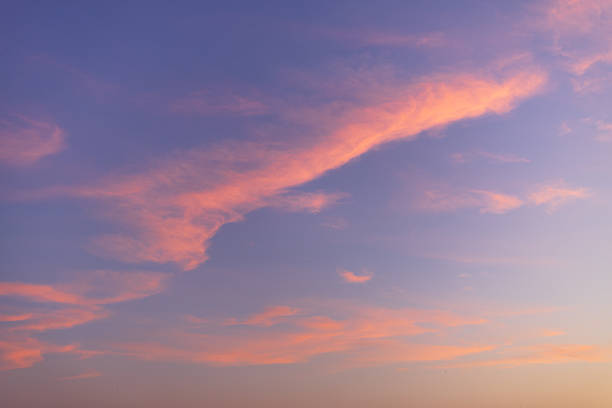 Beautiful twilight sky in shades of purple and pink with soft, wispy clouds during sunset. Ideal for use as a peaceful nature background, atmospheric wallpaper, or creative design element.