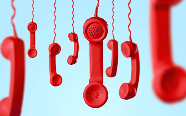 Multiple red vintage telephone handsets hanging against a light blue background, symbolizing communication, customer support, hotline services, call center operations, emergency contact and business connection concepts. Minimal and modern composition with strong color contrast, ideal for marketing, advertising and technology-related projects.