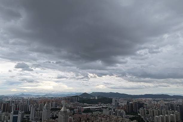 Urban cityscape under overcast sky with distant mountains and dense high-rise buildings