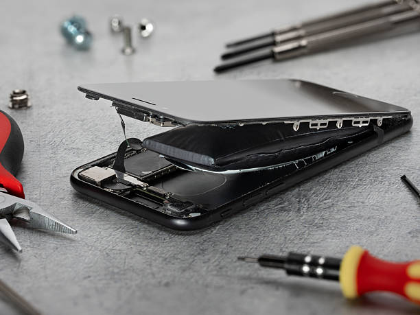 Smartphone with swollen lithium battery on workshop table with tools laying around.
