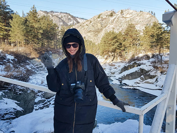 Smiling woman photographer posing on a bridge in winter