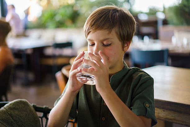 Boy drinking refreshing water from a glass .
