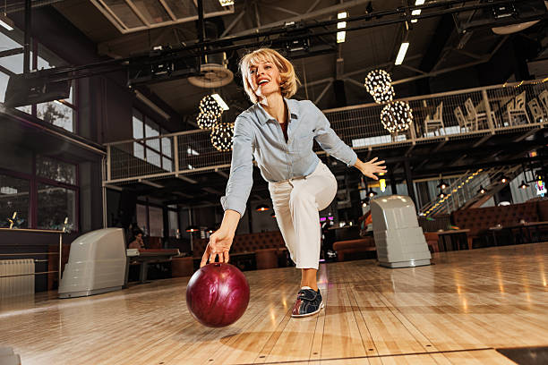 A portrait of a Japanese young woman in a bowling alley while holding a bowling ball.