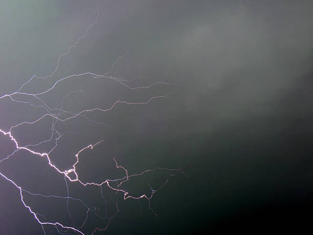 Lightning flashes across the dark sky during a storm. The scene shows a powerful display of nature as the storm unleashes its energy. Bright lines of lightning light up the clouds above.