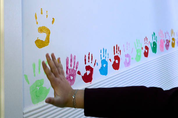 Hand touching a series of colorful painted handprints representing unity and creativity