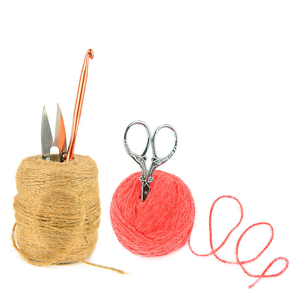 A flat lay photo of a ball of yarn and the string with knitting needles on a wooden table.