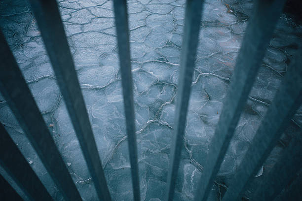 Frozen ice formations cover sections of Copenhagen's harbor waters in Denmark during an unusual winter cold snap on February 3, 2026. The thick ice layers create dramatic patterns across the normally navigable waterway. Metal barriers or railings are visible in the foreground, suggesting the view is from a waterfront promenade or bridge overlooking the frozen harbor.