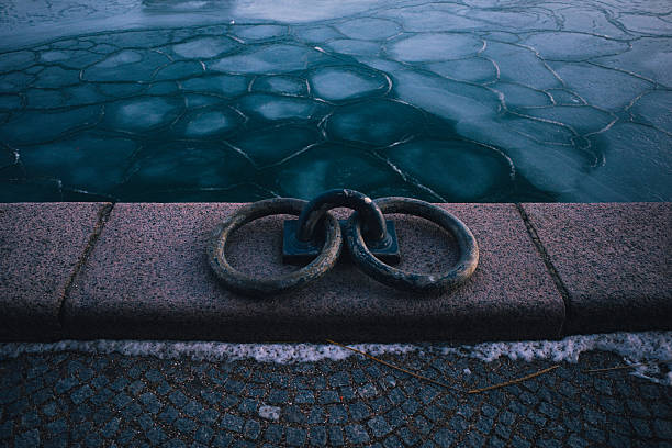Ice forms geometric patterns across Copenhagen Harbor in Denmark during an unusual winter cold snap on February 3, 2026. The frozen harbor water creates distinctive polygonal ice sheets, while mooring equipment remains visible along the waterfront. The extreme winter weather has transformed the normally navigable Danish waterway into a frozen landscape.