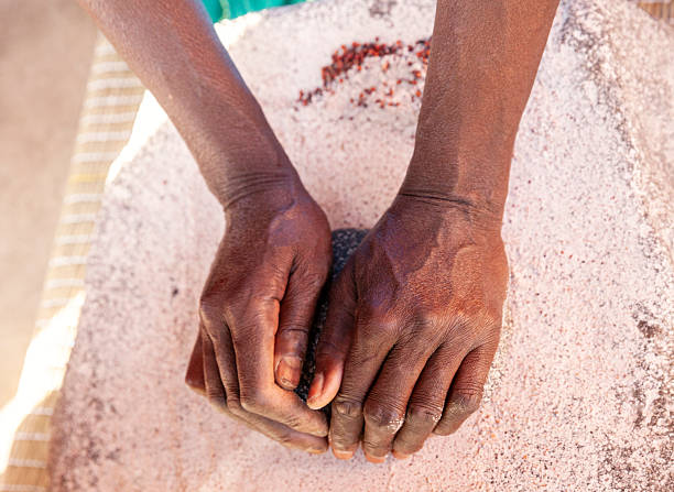 Woman using a  grinding stone to make flour