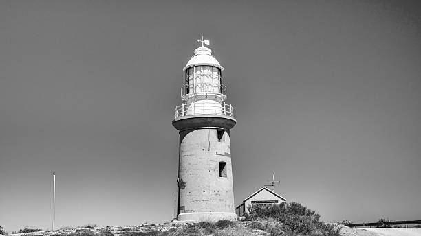 Scenic perspective of Vlamingh Head Lighthouse seen from highway showcasing lighthouse and surrounding landscape.