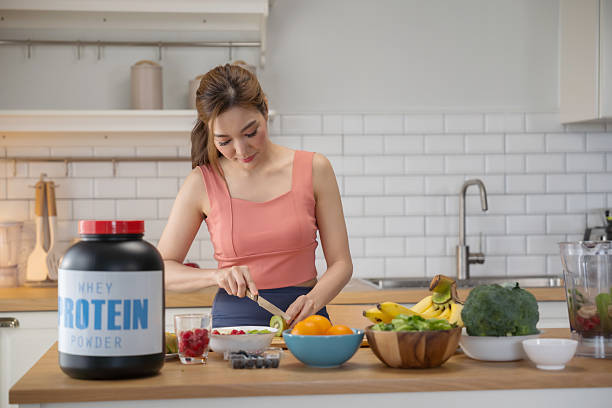 Asian woman cutting fresh kiwi and preparing healthy protein meal.