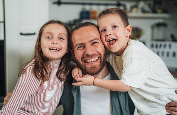 Happy family hugging and having fun at home. Father and children enjoying a joyful time together, family bonding, and quality time together