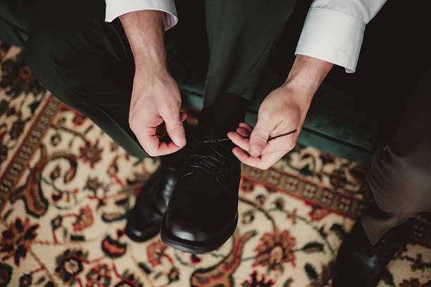Man in suit getting ready and tying dress shoes