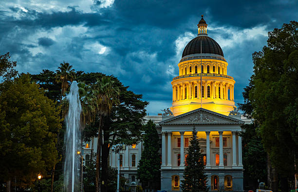 Drone shot of the California State Capitol amid downtown office buildings in Sacramento at sunset. \n\nAuthorization was obtained from the FAA for this operation in restricted airspace.