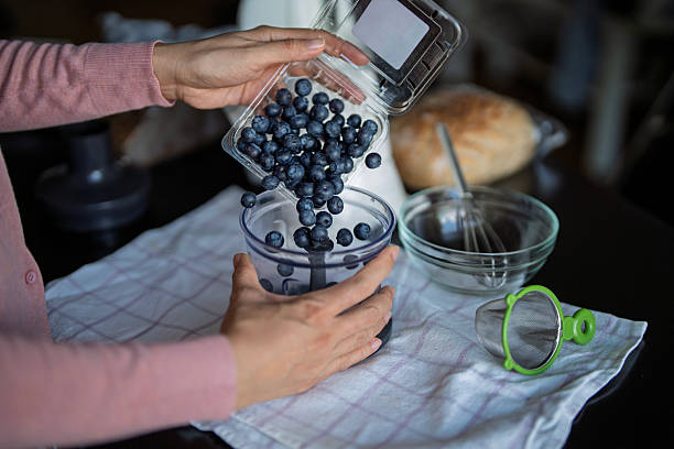 Hands Pouring Fresh Blueberries into Blender at Home