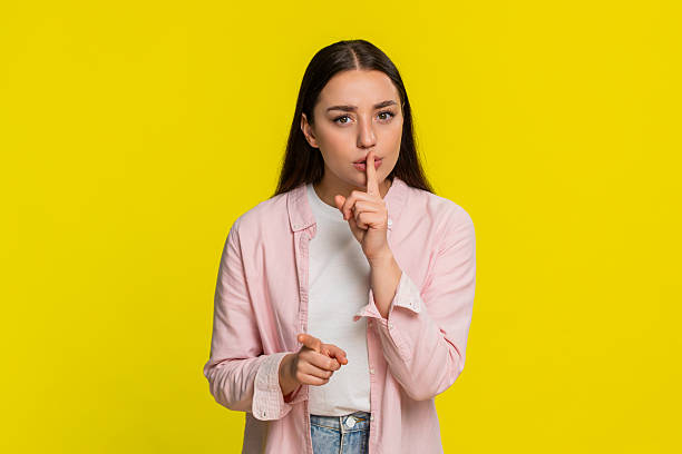 istock Woman placing finger on lips showing silence gesture asking for quiet serious thoughtful expression 2260489566