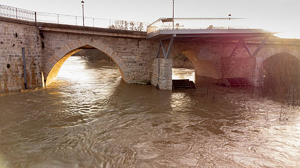 Flooding of the Duero River with high water levels that submerge the wheels of an old, abandoned watermill under the old stone bridge in Tordesillas, Spain