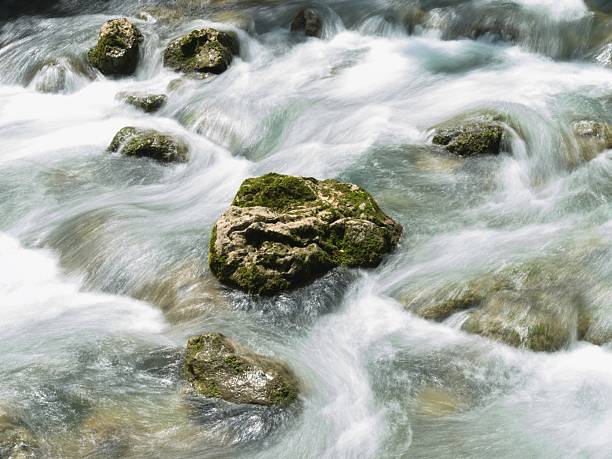 Rapid flowing water cascading over moss-covered rocks in a mountain stream