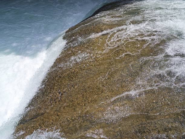 Water flowing over a rocky surface with white foam and clear stream