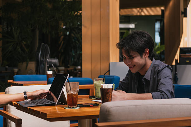 Young Asian man smiling while working remotely at cafe