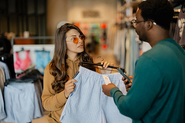 Sales assistant using a tablet to check stock availability and clothing size in a boutique store. Modern retail, customer support and fashion shopping concept.