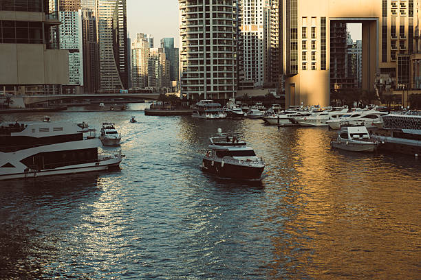 Dubai Marina before sunset with skyscrapers, boats and reflections in the water, United Arab Emirates