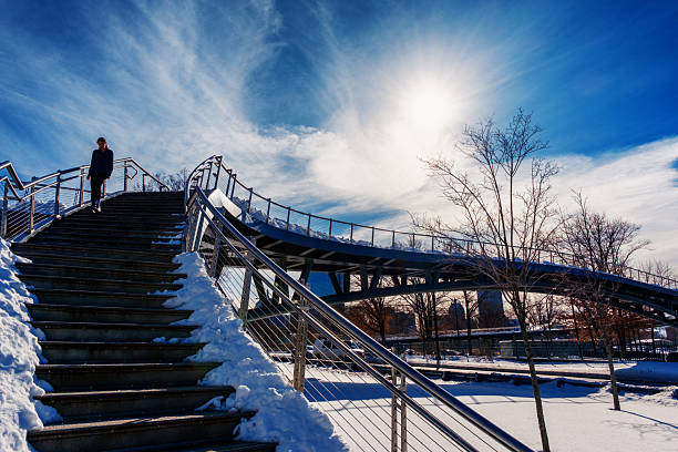 Boston, Massachusetts, USA - February 2, 2026: A women on the stairs of the Frances Appleton Bridge on a winter day. The Frances Appleton Bridge is a pedestrian bridge in Boston, Massachusetts that opened on August 31, 2018. The bridge, which crosses Storrow Drive to the Charles River Esplanade, is named in recognition of the celebrated courtship and marriage of Frances Fanny Appleton and Henry Wadsworth Longfellow, after whom an adjacent larger bridge is named.